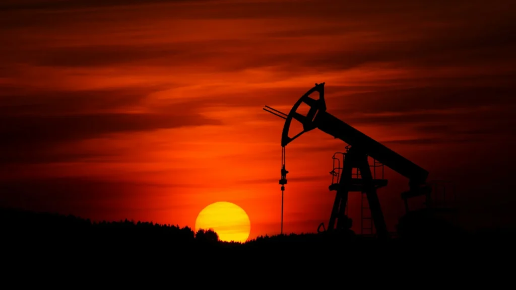 Cinematic shot of a desert sunset behind an oil rig with a glowing red arrow shattering a glass oil barrel in the foreground